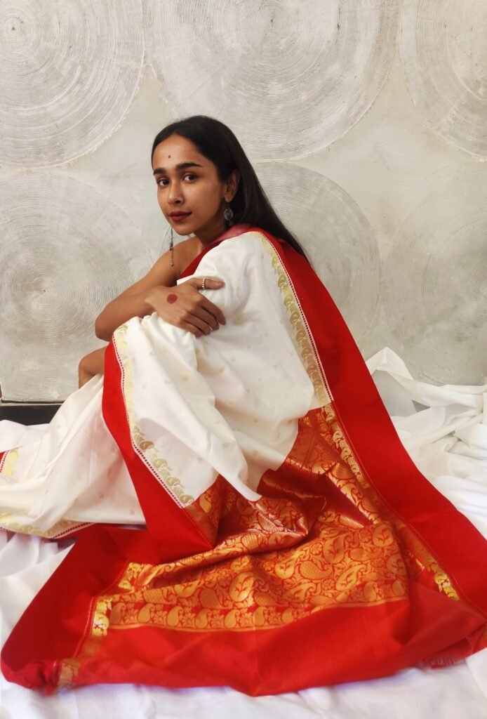 Envelope yourself in the resplendence of laal paar sada saree, adorned with  embroidered motifs all over the body and maa lokkhi on the… | Instagram